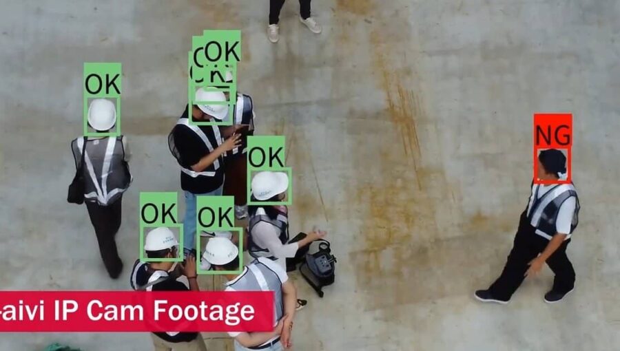 Real-time safety inspection on a construction site, captured via drone footage, using META-aivi AR + AI vision (green 'OK' boxes) to verify PPE (hard hats) and flagging a violation with a red 'NG' box.